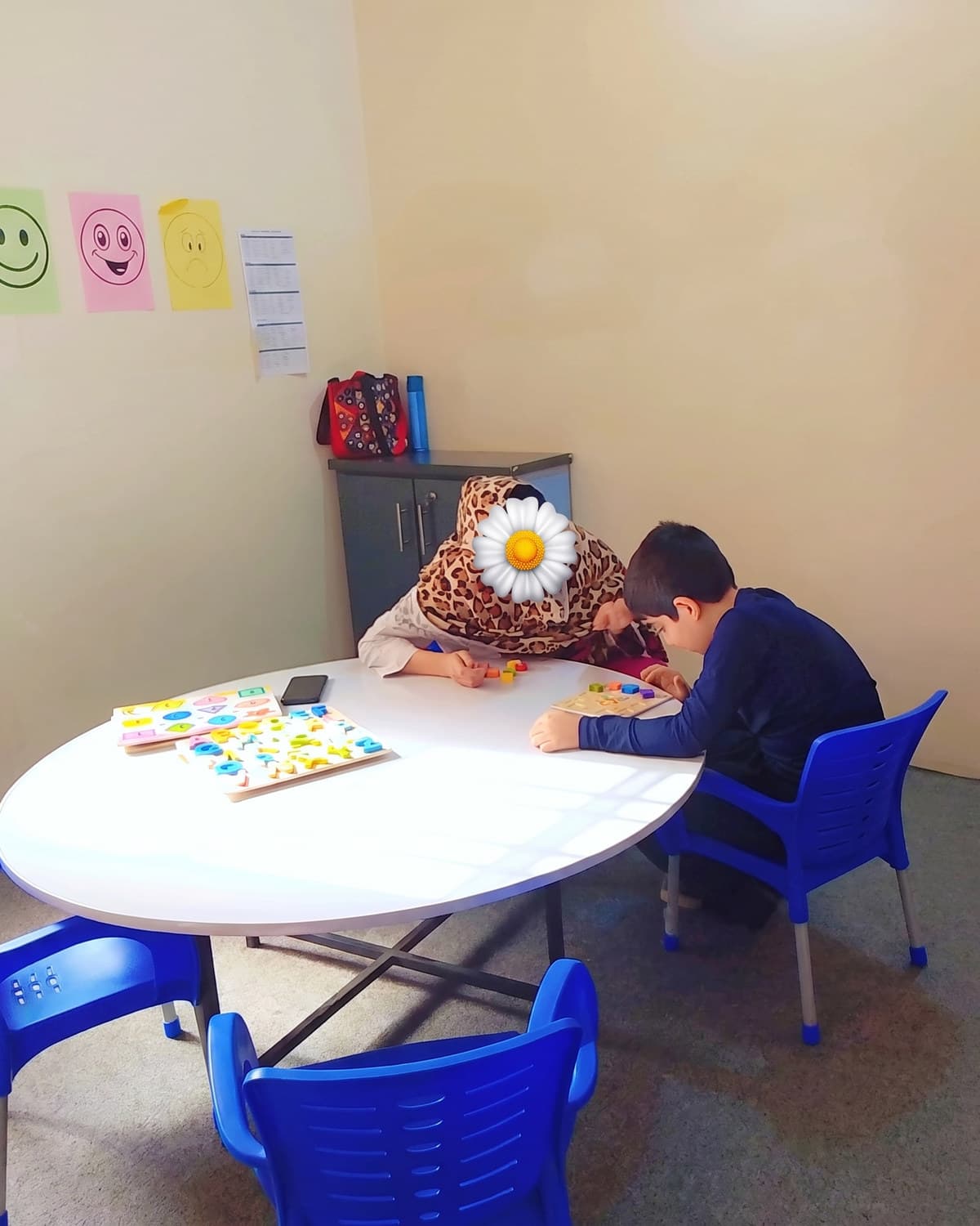 Two children sorting coloured tiles at the round classroom table