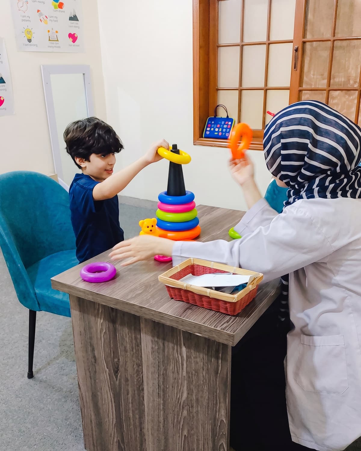 A child stacking coloured rings with their therapist