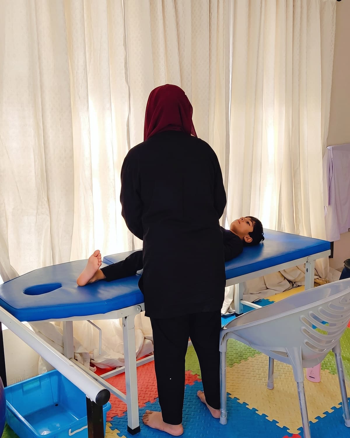 A therapist supporting a child during a session on the therapy table