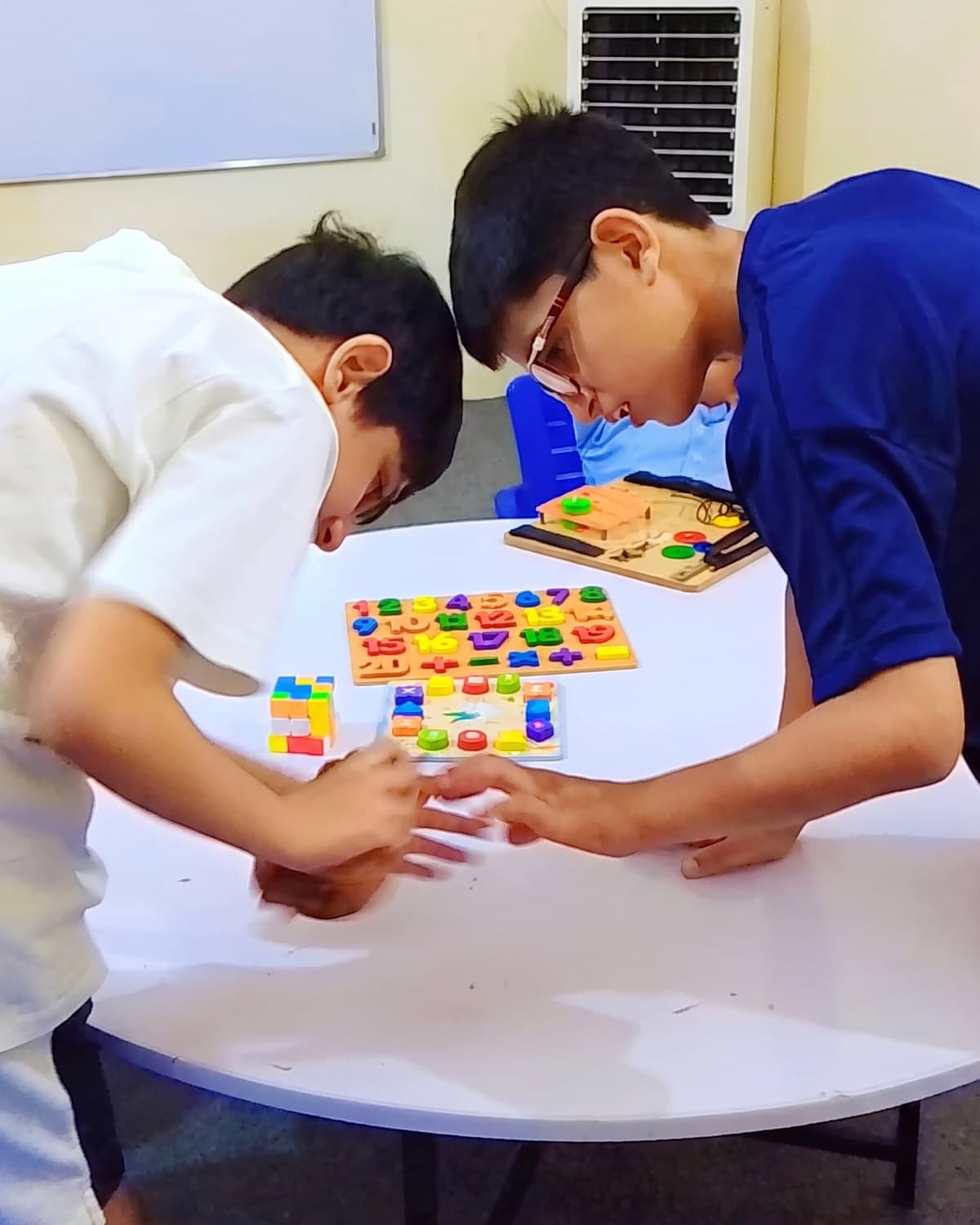 Two older students building a pattern with coloured tiles