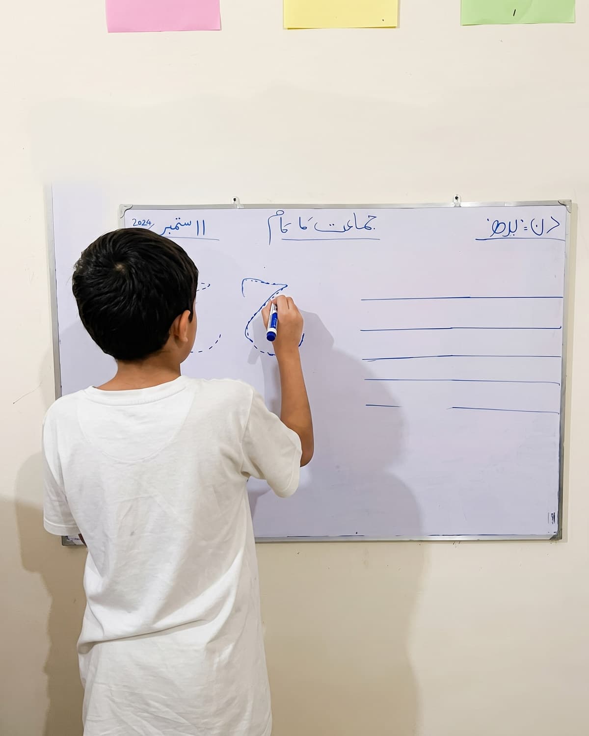 A boy practising his writing on the classroom whiteboard