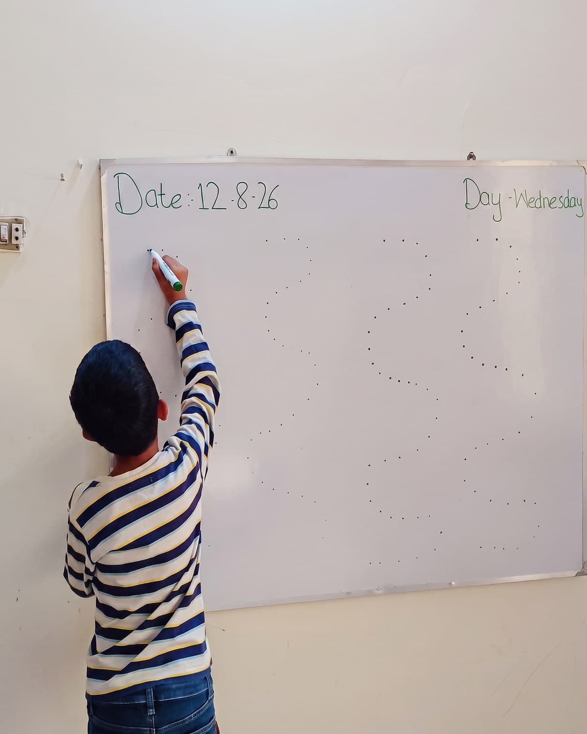 A boy working through a task at the whiteboard