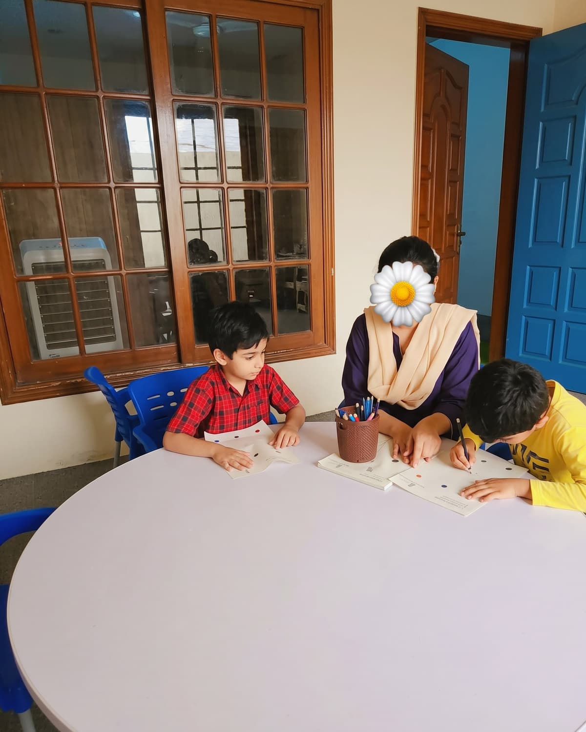 A teacher and children working around the round table