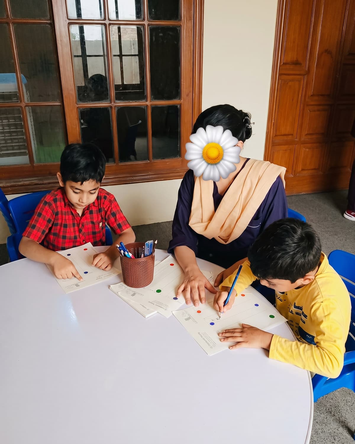 A teacher supporting two children with a table-top activity