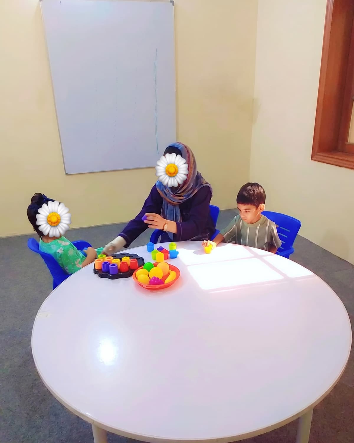 Children exploring coloured toys around the big white table